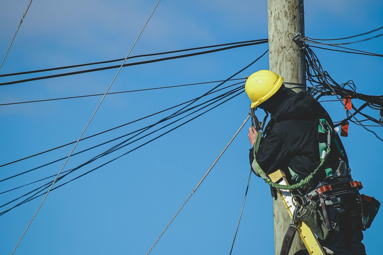 Technician in a hard hat working on a utility pole
