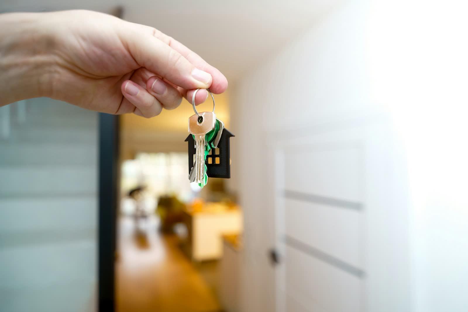 Hand holding house keys in front of a front door